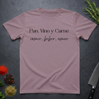 Paragon colored t-shirt with Spanish text "Pan, Vino y Carne" on a dark surface with decorative elements. 