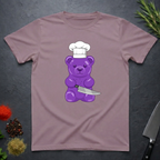 Paragon colored t-shirt with a purple bear wearing a chef's hat and holding a knife on a dark surface.