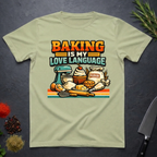 Pistachio green t-shirt with baking-themed graphic and text "Baking is My Love Language" on a dark surface.