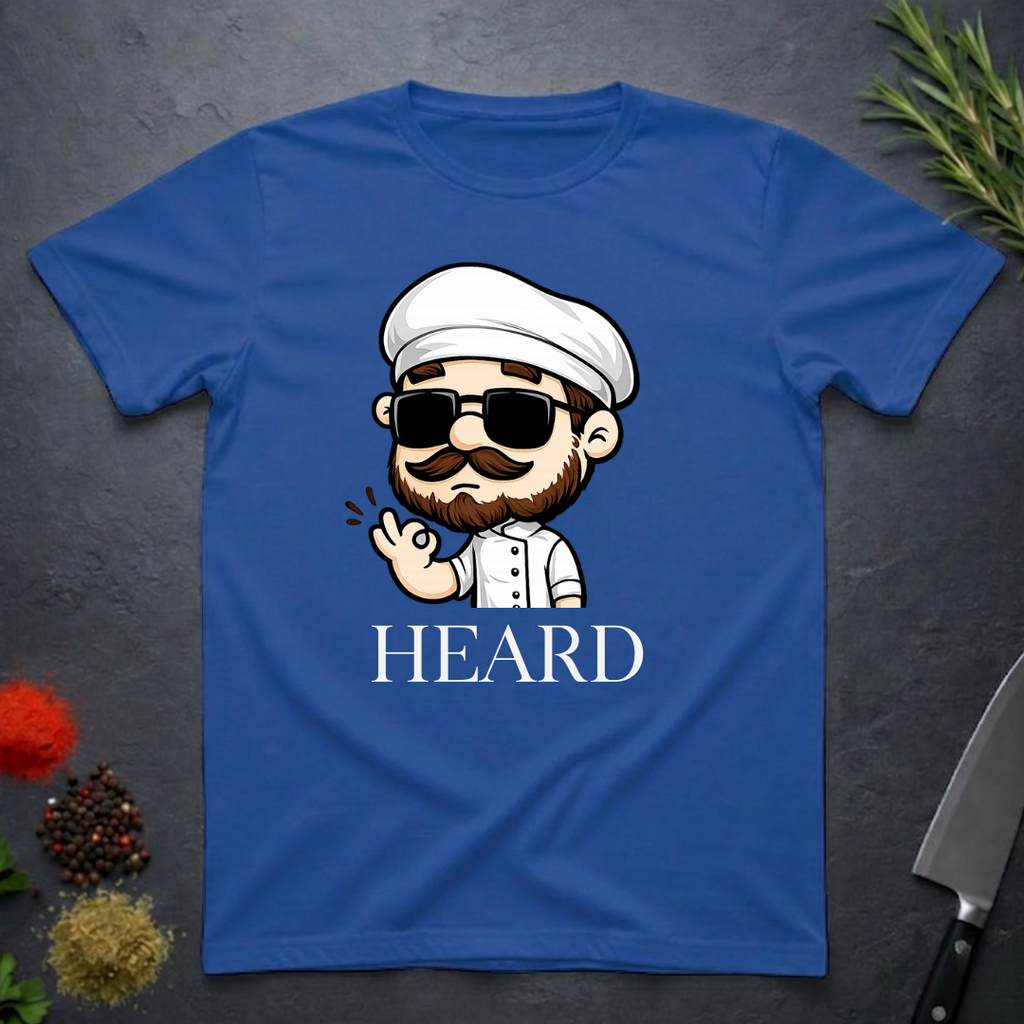 Royal blue t-shirt with a cartoon character chef and 'HEARD' text on a dark surface.