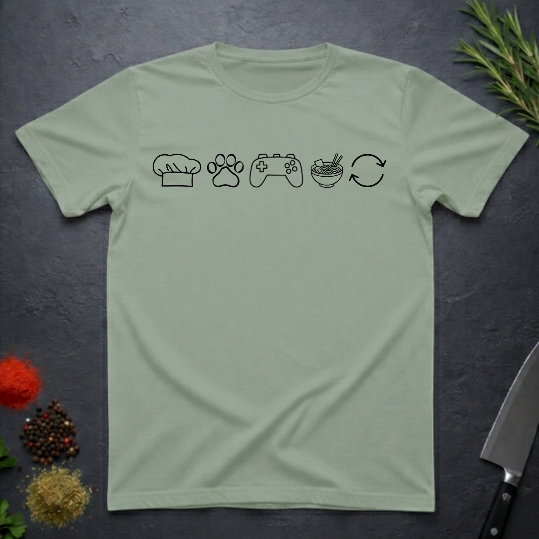 Sage green t-shirt with black icons of chef hat, paw print, game remote, ramen bowl and repeat symbol on a dark surface.