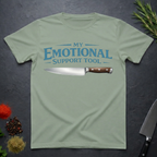 Sage Green t-shirt with a knife graphic and teal text "My Emotional Support Tool" on a dark surface.