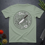 Sage green t-shirt with a circular floral and knife design on a dark surface.