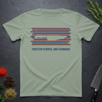 Sage green t-shirt with 13 red, white, and blue stripes with a cut out (negative space) image of a chef's knife and text "THIRTEEN STRIPES. ONE STANDARD." on a dark surface.