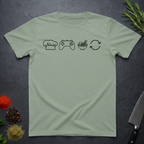 Sage green t-shirt with black icons of chef hat, game remote, ramen bowl and repeat symbol on a dark surface.