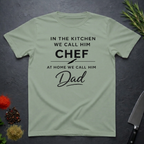 Sage Green t-shirt for Father's with text "In the kitchen we call him Chef - At home we call him Dad" on a dark surface.