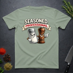 Sage Green t-shirt with cartoon salt and pepper shakers and 'Seasoned Professional' text on a dark surface.
