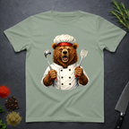 Sage green t-shirt with a grizzly bear chef holding utensils design on a dark surface.
