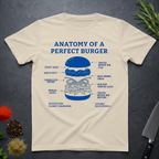 Sand colored t-shirt with 'Anatomy of a Perfect Burger' graphic on a dark surface.