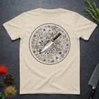 Sand colored t-shirt with a circular floral and knife design on a dark surface.