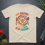 Sand colored t-shirt with colorful African graphic and text "Our Culture Our Kitchen, our Cuisine: on a dark surface.