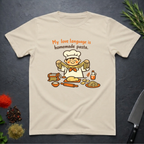 Sand colored t-shirt with a cartoon chef and pasta graphic on a dark surface with text "My love language is homemade pasts" on a dark surface.