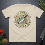 Sand colored t-shirt with a circular knife and colored floral design on a dark surface.