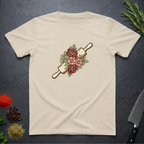 Sand colored t-shirt with a rolling pin and floral design on a dark surface.