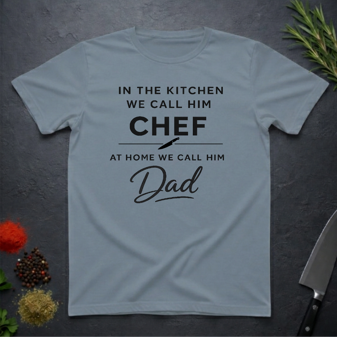 Stone blue t-shirt for Father's with text "In the kitchen we call him Chef - At home we call him Dad" on a dark surface.
