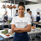 Student in a kitchen wearing a shirt with 'Earned, Not Given - Culinary Class of 2026' text, surrounded by cooking equipment and ingredients.