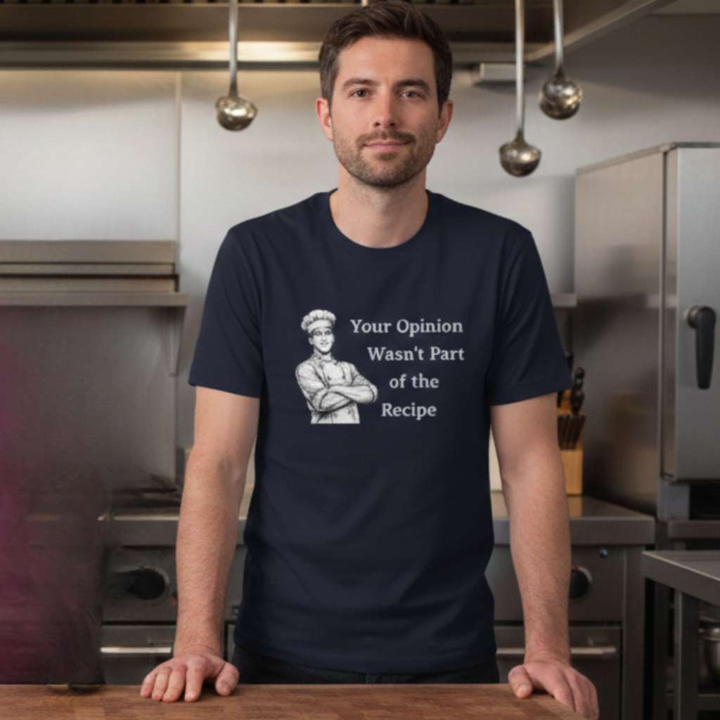 Man wearing a navy blue t-shirt  t-shirt with a male chef graphic and text "Your Opinion Wasn't Part of the Recipe" in a kitchen setting.