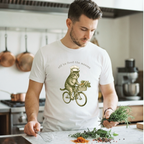 Man in a kitchen wearing a white t-shirt with a cat riding a bike graphic, holding herbs.