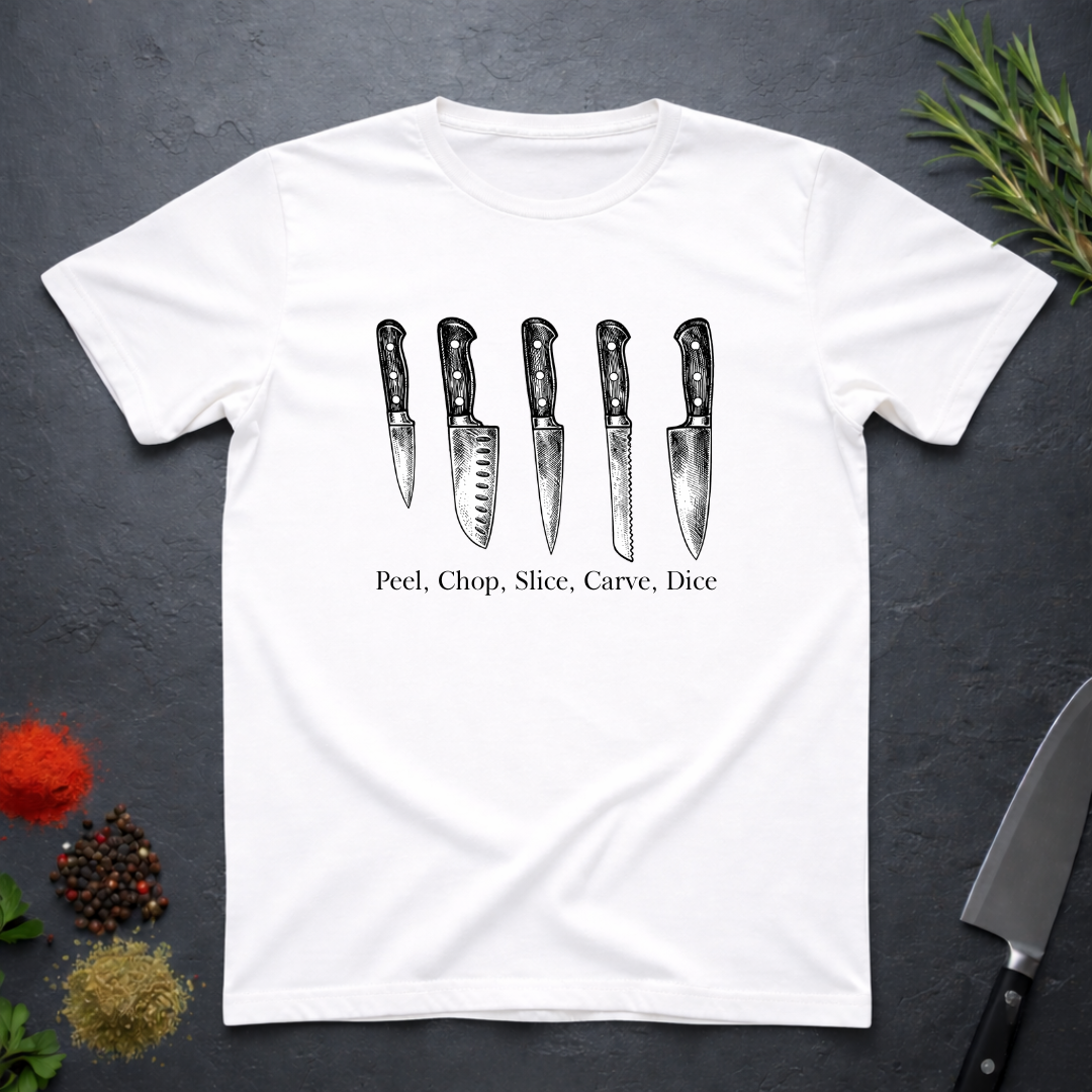 White t-shirt with knife graphic and text 'Peel, Chop, Slice, Carve, Dice' on a dark surface with kitchen items.