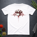 White t-shirt with a chef hat and heartbeat design on a dark surface with kitchen items.