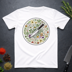 White t-shirt with a circular knife and colored floral design on a dark surface.