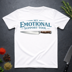 White t-shirt with a knife graphic and teal text "My Emotional Support Tool" on a dark surface.