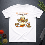 White t-shirt with a cartoon chef and pasta graphic on a dark surface with text "My love language is homemade pasts" on a dark surface.